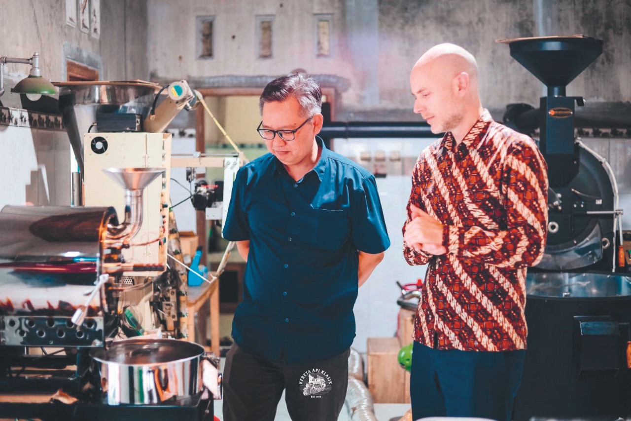 KONSISTEN: Ardian Purwoseputro menunjukkan proses roasting Kopi Kereta Api kepada konjen US di Surabaya, Chris Green.
