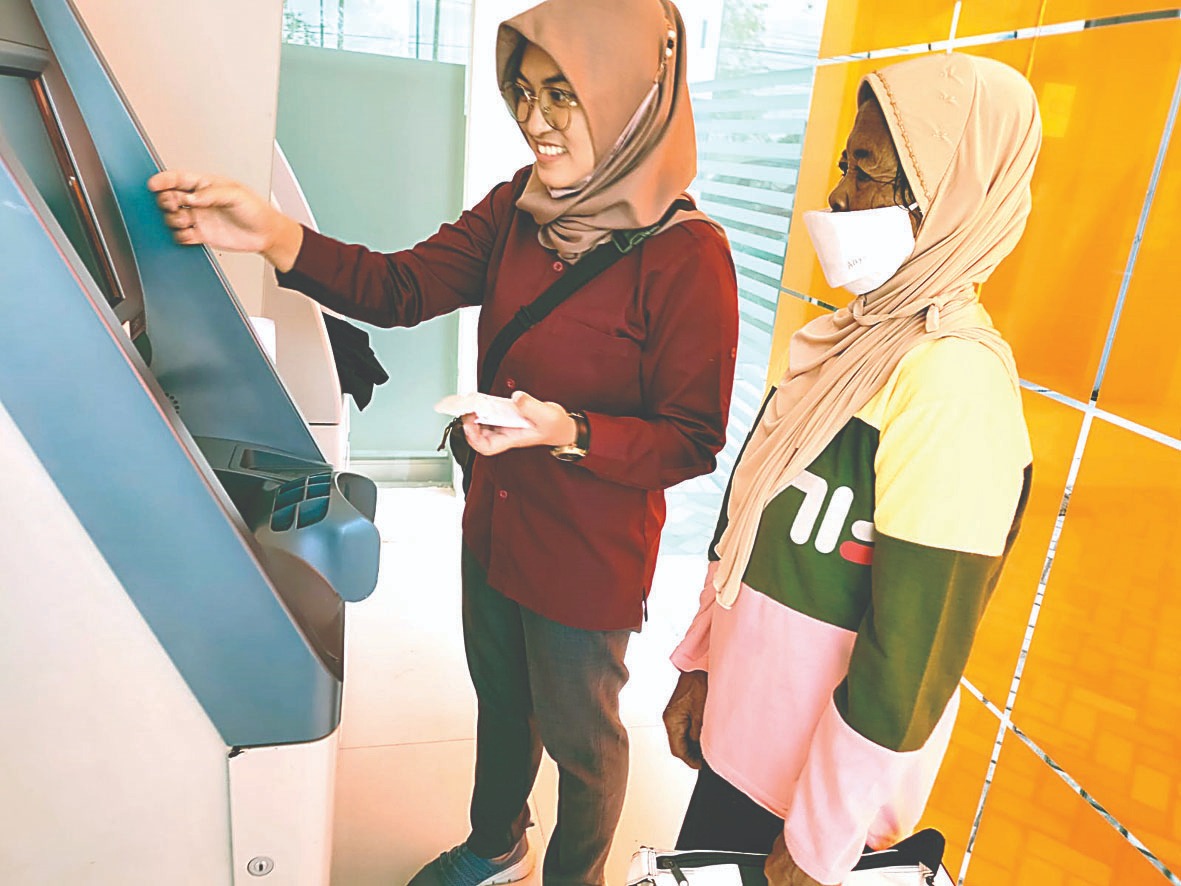 BUTUH: Petugas PKH saat menuntun penerima mengambil uang di salah satu ATM beberapa waktu lalu.