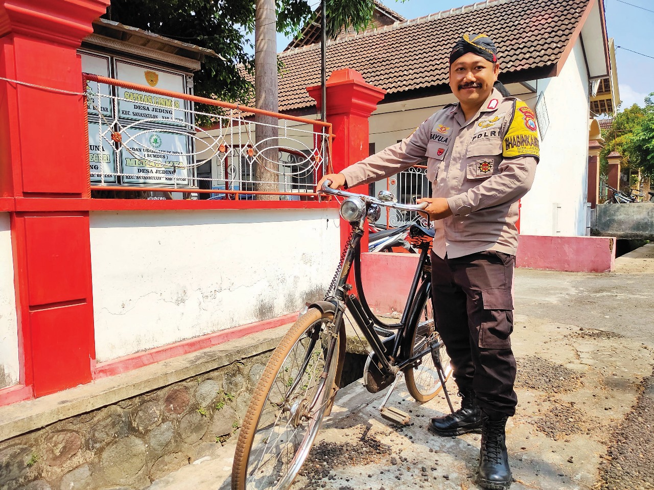 BANGGA: Bripka Bayu Ariyanto dengan sepeda onthel yang digunakan untuk menyambagi warga Desa Jeding, Kecamatan Sanankulon, Kabupaten Blitar.