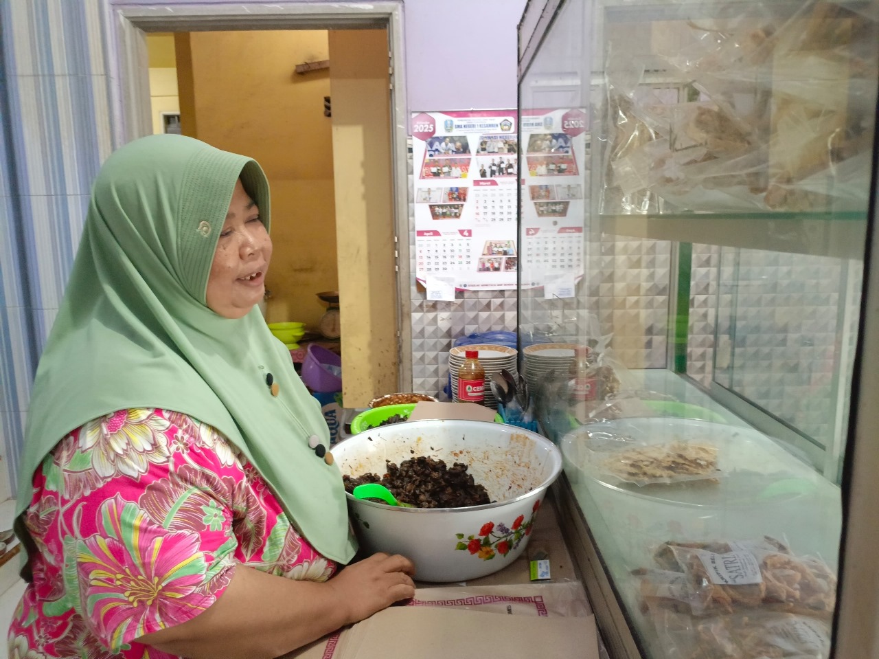 Bu Karti saat melayani pembeli di warungnya beberapa waktu lalu.