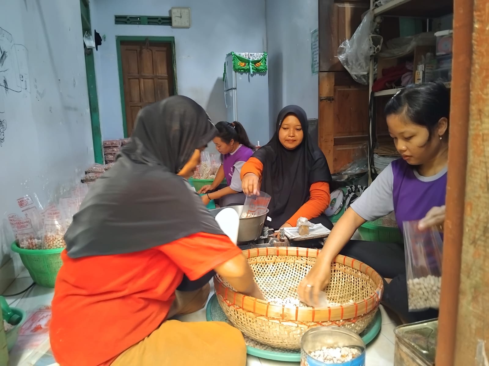 TEGUH: Binti Zulaikah sedang membantu beberapa pekerja yang sedang mengemasi kacang sanghai.