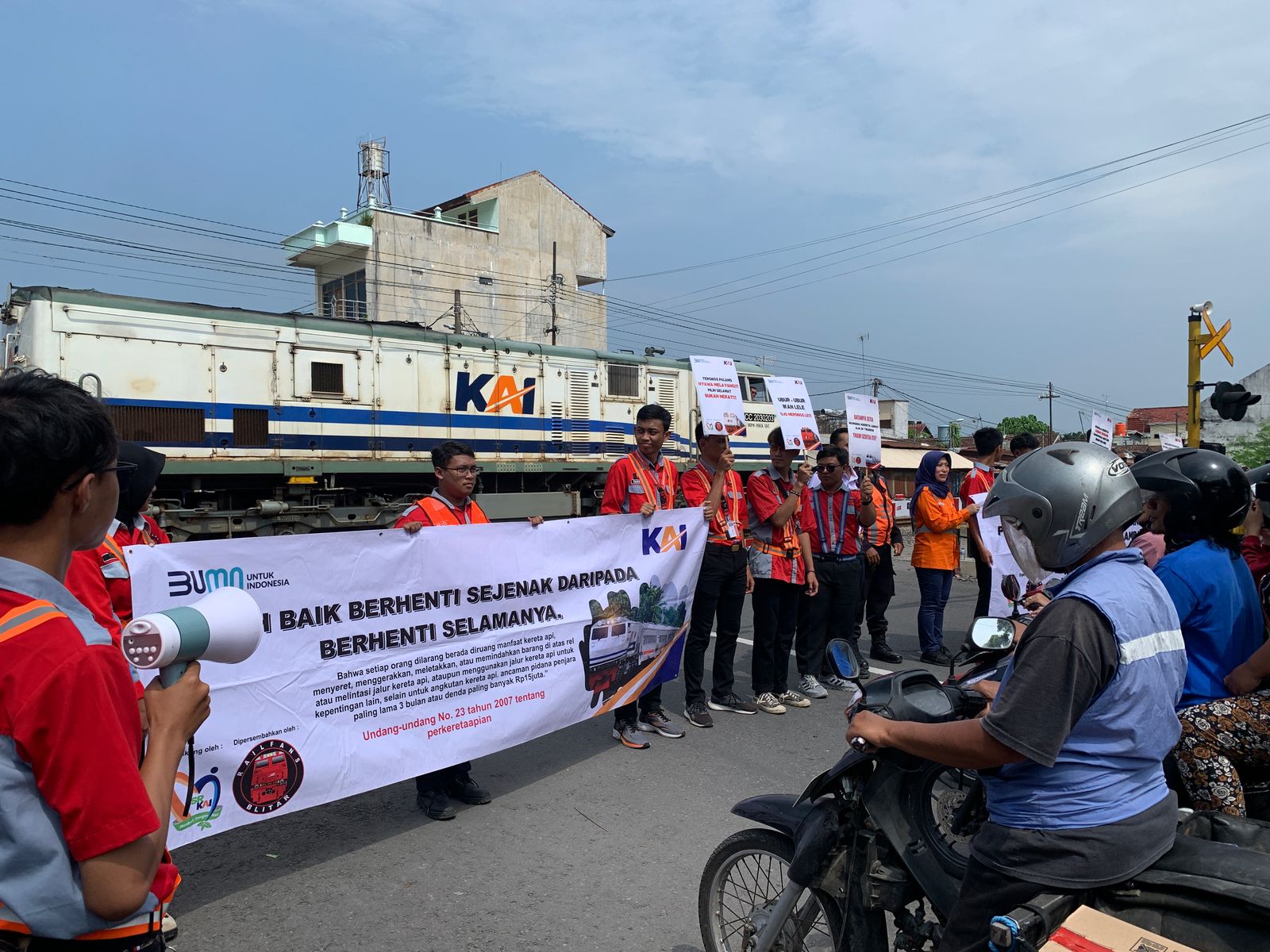 AKSI TURUN JALAN: Railfans Blitar membentangkan poster untuk sosialisasi sekaligus edukasi tentang keselamatan di perlintasan sebidang KA kepada pengendara, Selasa (20/5/2025).