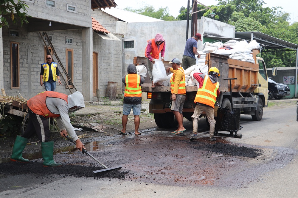 TUNGGU ANGGARAN: Pekerja proyek melakukan perbaikan jalan melalui skema URC yang kini terhenti karena kehabisan bahan.
