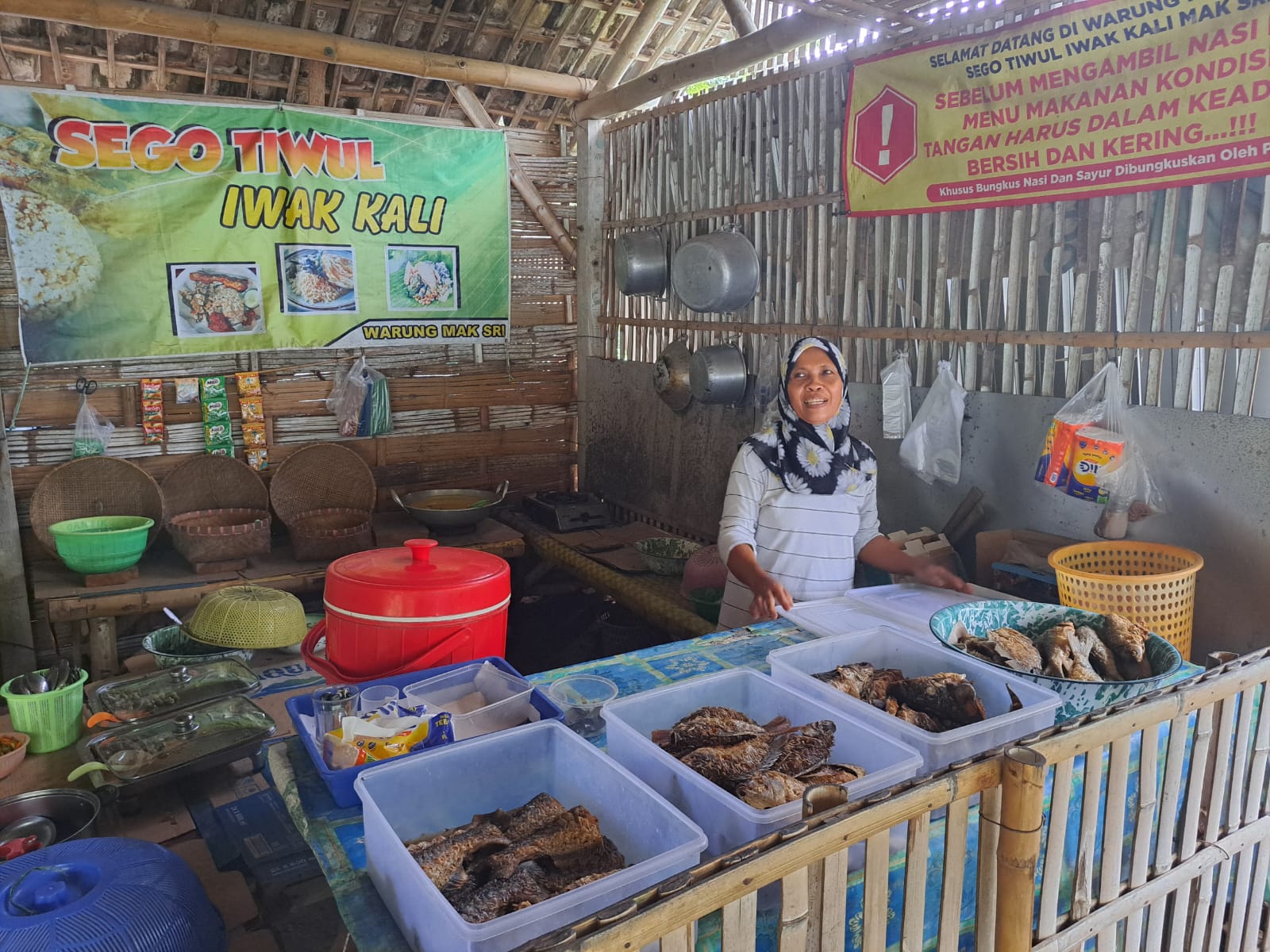 Pini menyajikan masakan di Warung Iwak Kali Mak Sri di Desa Selokajang, Srengat.