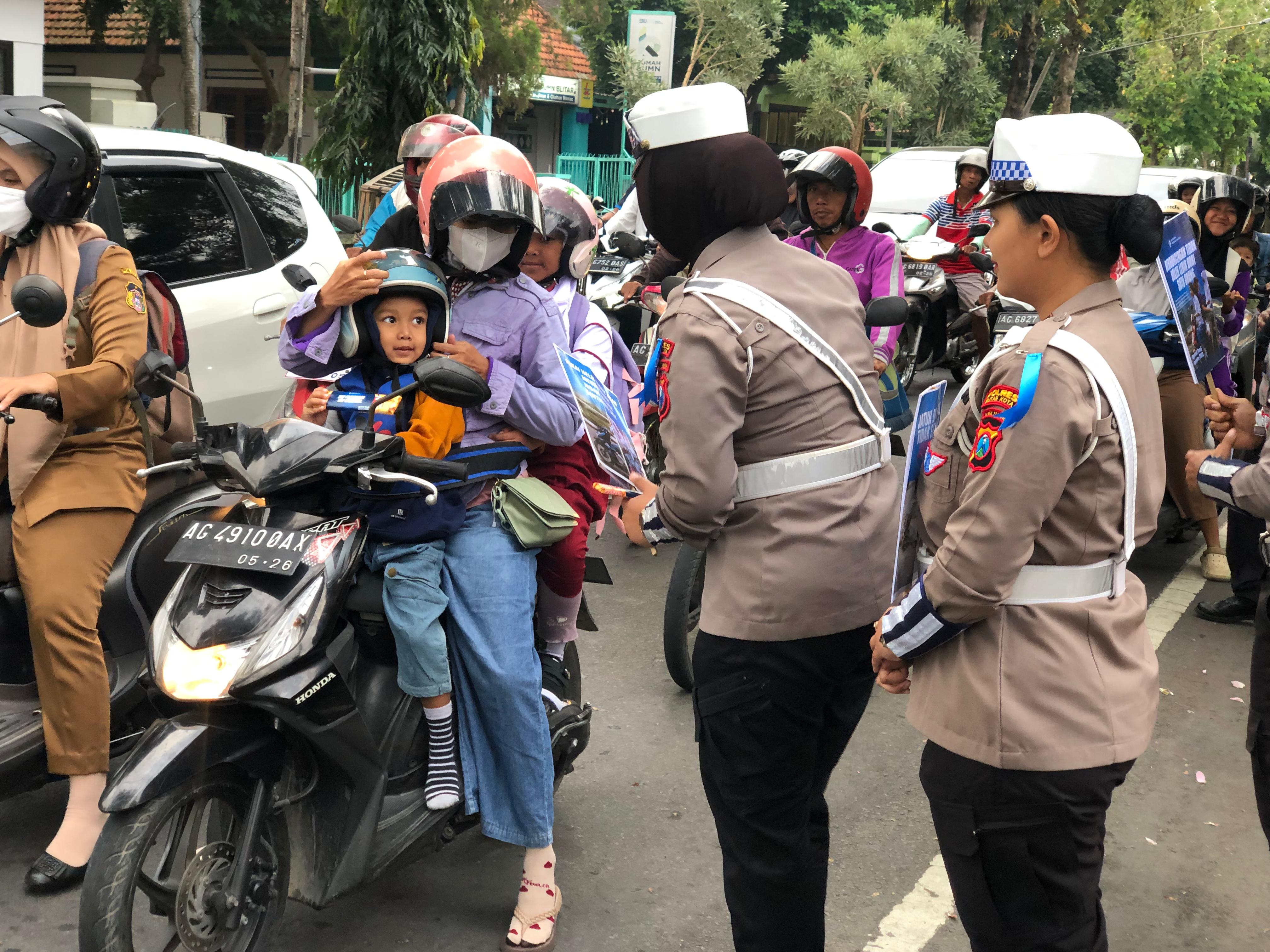 BAIK: Polisi memberikan helm dan coklat kepada pengendara yang ketahuan anaknya tidak menggunakan helm, Selasa (15/7/2025).