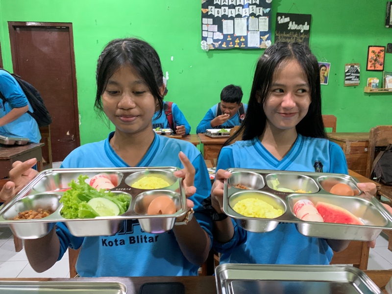 LEZAT: Dua siswi SMPN 4 Blitar menunjukkan seporsi MBG yang mulai didistribusikan SPPG ke sekolah, kemarin (19/8/2025).