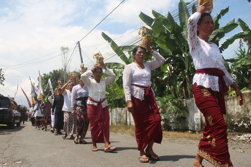 BERSYUKUR: Umat Hindu berjalan sambil menyunggi sesaji yang digunakan dalam rangkaian upacara Piodalan di Pura Setya Dharma, Desa Pasirharjo, Kecamatan Talun.