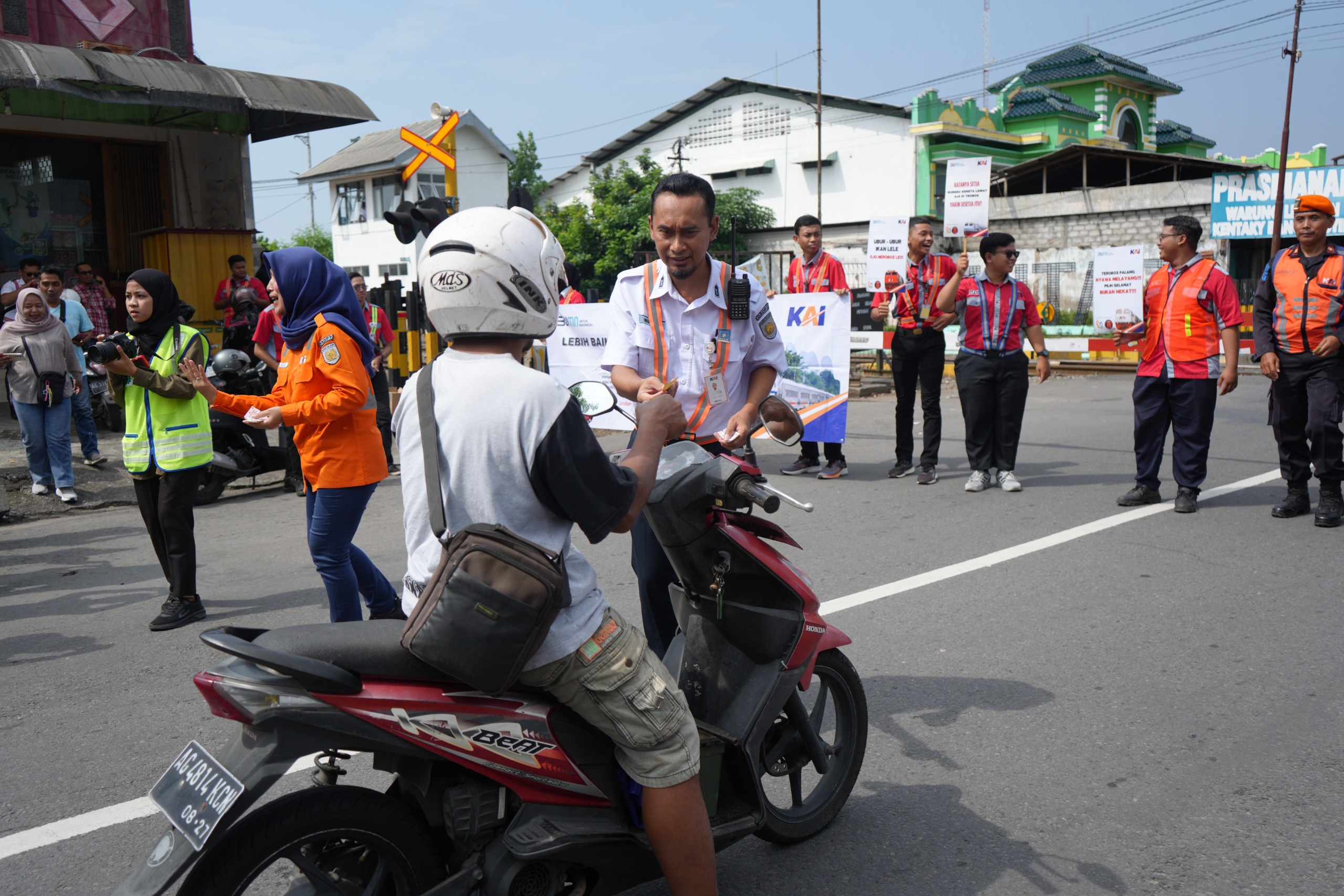 HATI-HATI YA: Petugas KAI memberikan selebaran sosialisasi keselamatan kepada pengguna jalan di salah satu perlintasan sebidang berpalang pintu di Jalan Anggrek Kota Blitar beberapa waktu lalu.