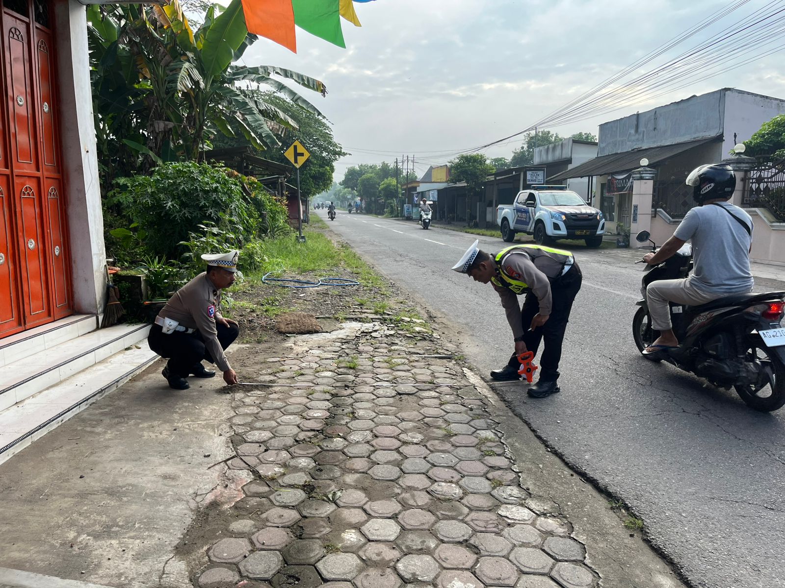 &lrm;PENDALAMAN: Personel Satlantas Polres Blitar Kota tengah mengecek TKP korban tabrak lari di Desa Maron, Kecamatan Srengat, Senin (19/1/2026).