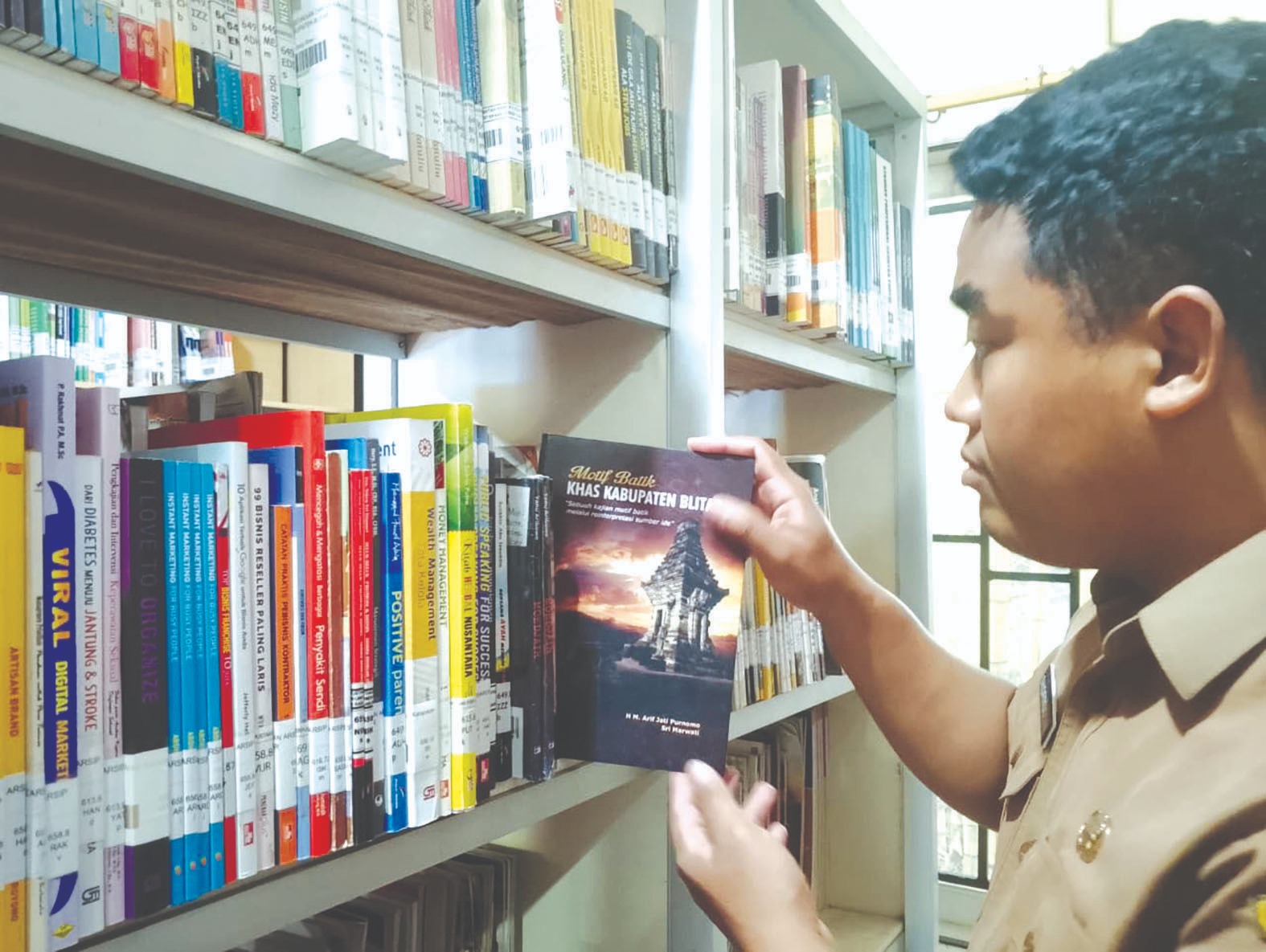 Pegawai dispusip sedang memeriksa sejumlah koleksi di perpustakaan.