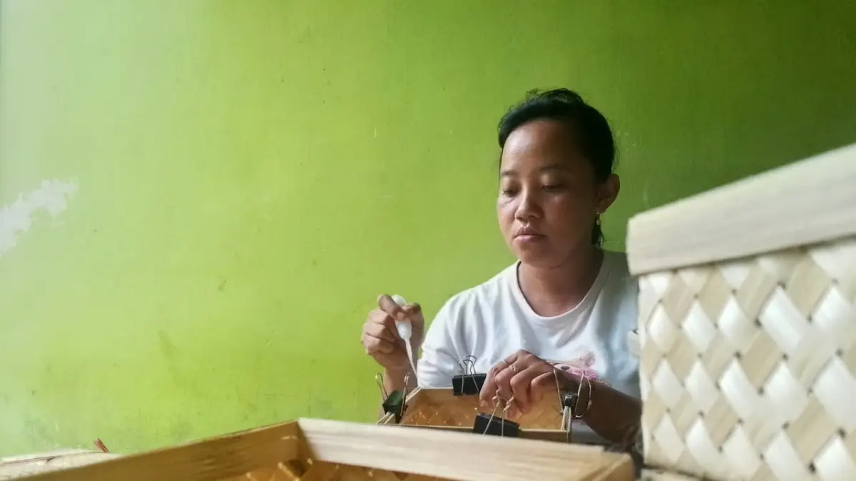 AKHMAD NUR KHOIRI/RADAR BLITAR - JAGA WARISAN: Hesti Retno Satuti mengerjakan anyaman bambu pesanan konsumen beberapa waktu lalu.