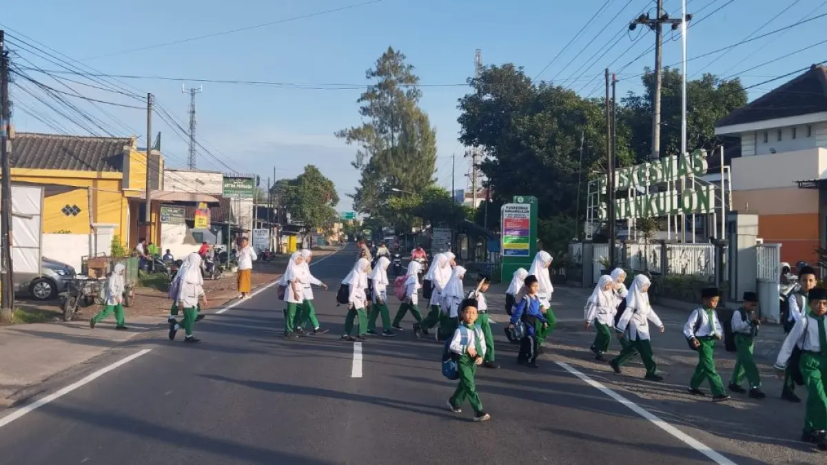 POLSEK SANANKULON UNTUK RADAR BLITAR 
RAWAN: Sejumlah siswa menyeberang jalan dengan dipandu personel Polsek Sanankulon, kemarin (17/6). 
