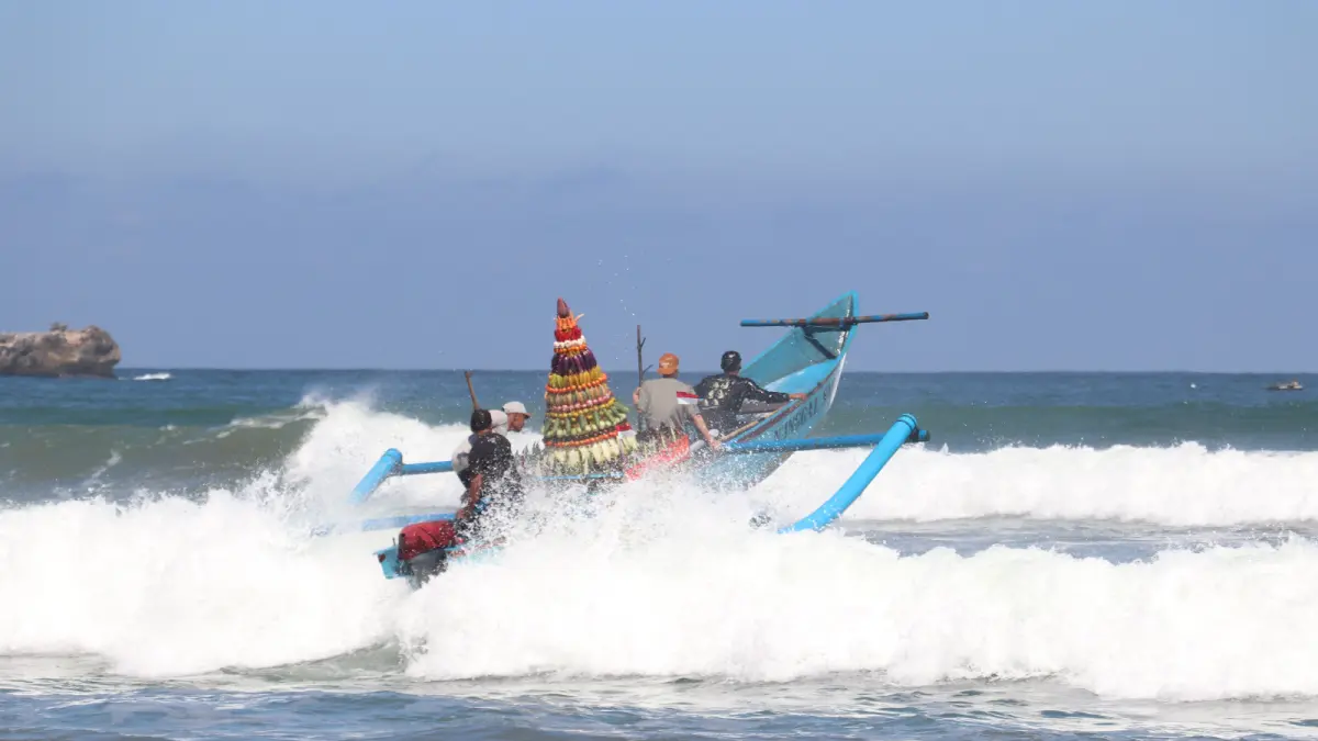 Warga membawa sesaji yang akan dilarung saat Upacara tradisi larung sedekah laut di Pantai Serang, kemarin (18/6).