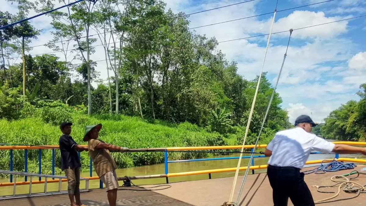 JADI JUJUKAN: Seorang awak perahu tambangan di Blitar menarik tali penambat untuk menyeberangkan pengendara di Sungai Brantas.
