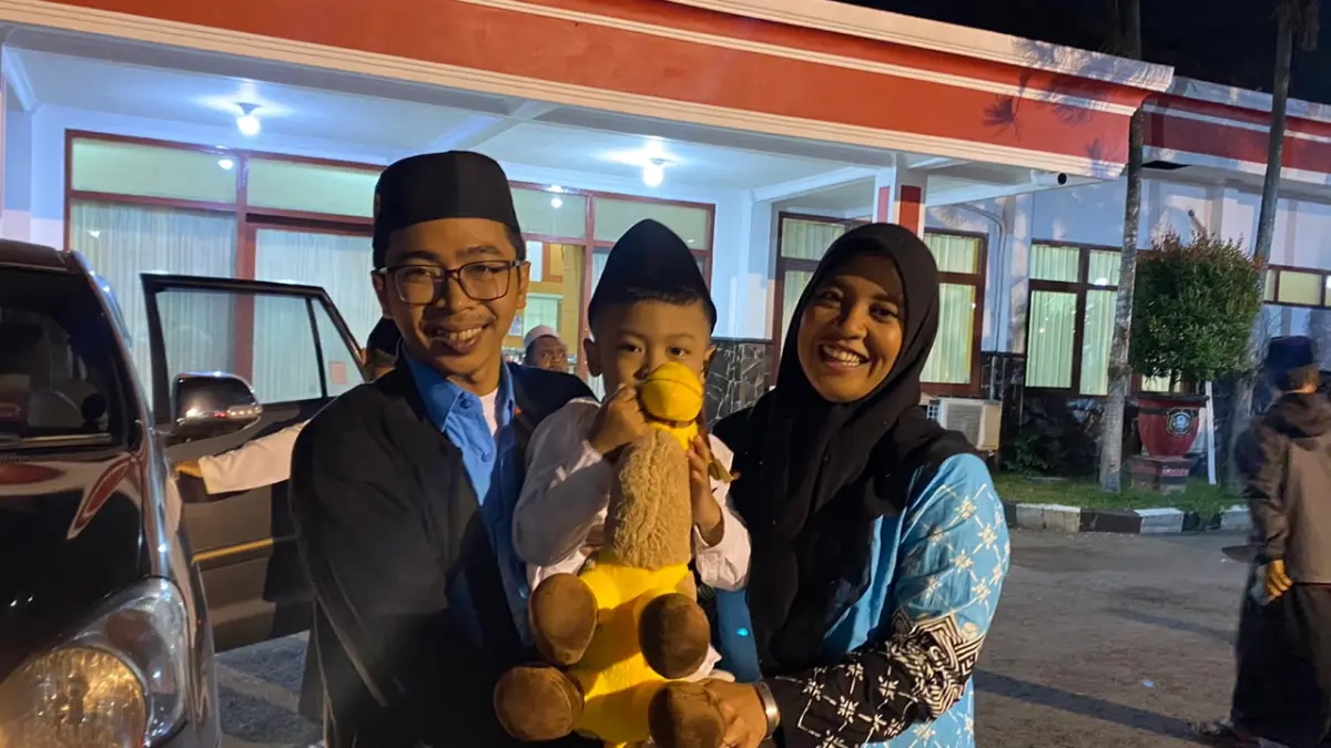 BUAH TANGAN: Jemaah haji asal Gedog, Choirul dan Riza, memeluk buah hatinya setiba di Balai Kota Koesoemo Wicitro, Minggu (28/6) malam, sambil membawa boneka unta oleh-oleh dari Madinah.