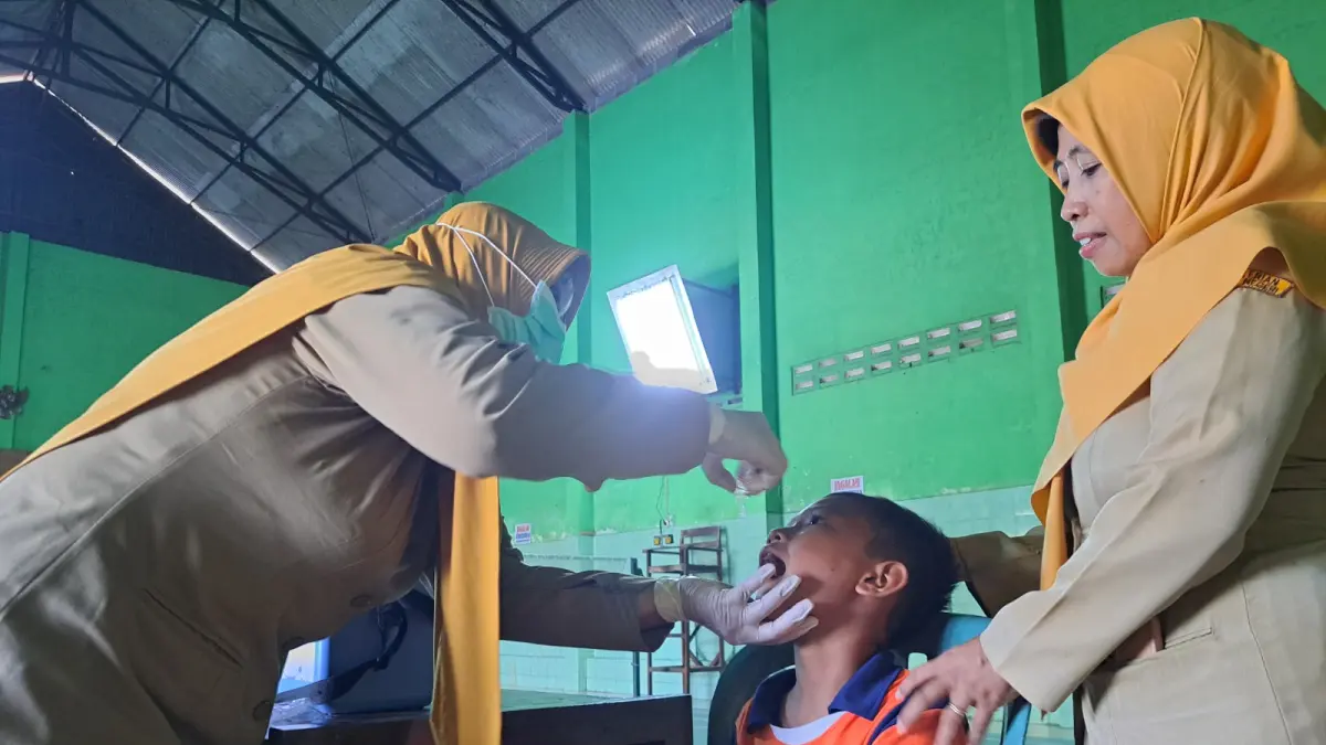 Petugas kesehatan memberikan imunisasi kepada seorang siswa dalam pelaksanaan Bulan Imunisasi Anak Sekolah (BIAS). Dinkes Kabupaten Blitar memastikan kualitas vaksin tetap terjaga melalui pengawasan ketat sistem rantai dingin (cold chain) sebelum didistribusikan ke sekolah-sekolah.