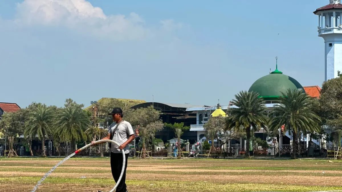 DAMPAK BAZAR : Petugas DLH Kota Blitar menyiramkan air ke rumput alun alun yang mengering usai pelaksanaan bazar Blitar Djadoel 2026.