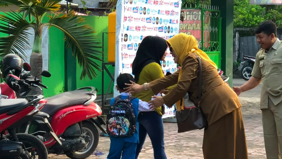 Seorang guru menyambut siswa baru di salah satu SD di Kota Blitar.
