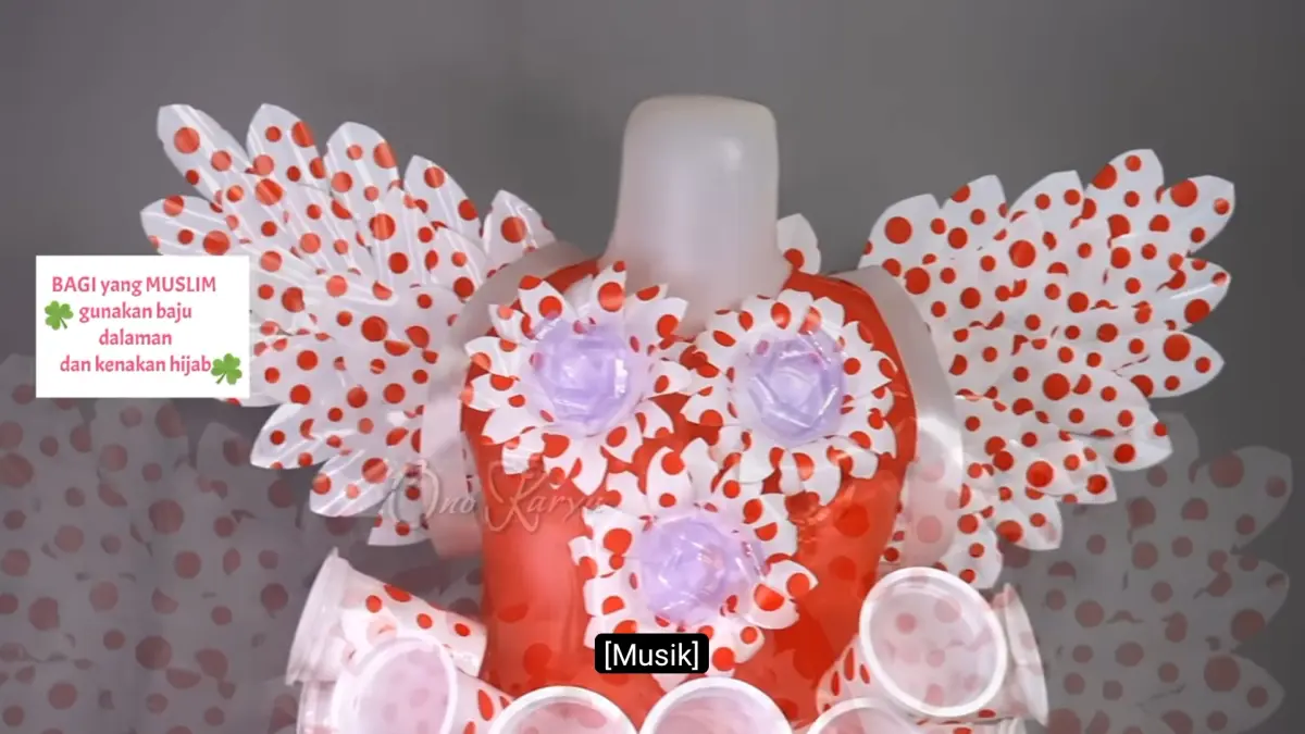Kostum dari plastik kresek dibuat menjadi gaun bersayap dengan hiasan bunga dan bulu dari gelas plastik bekas.