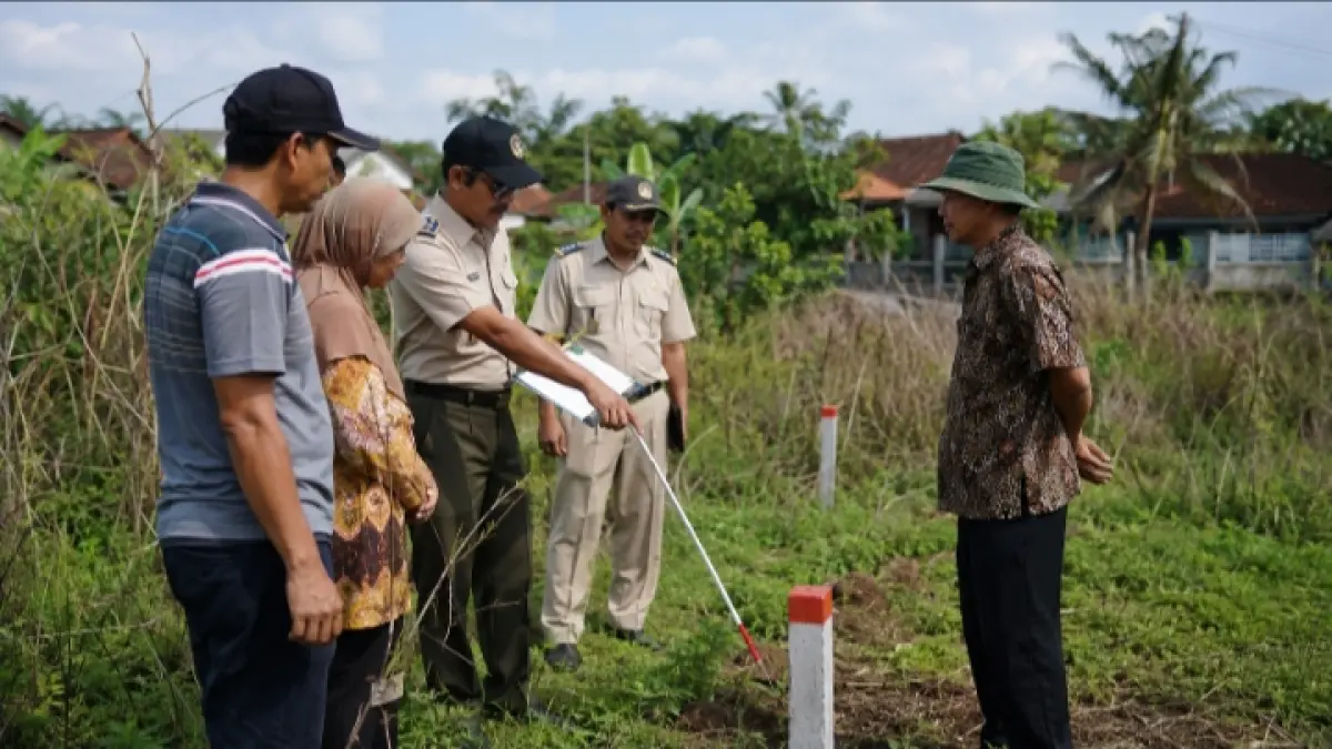 Petugas pertanahan bersama pemohon dan saksi melakukan pemeriksaan fisik serta pengukuran batas bidang tanah di lapangan.
