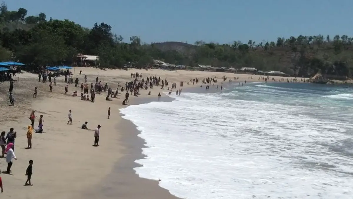 Pantai Tambakrejo Blitar ramai saat Minggu sore. Air biru kehijauan, pasir putih, warung ikan asap, dan pemecah ombak jadi daya tarik.(Pinterest)
