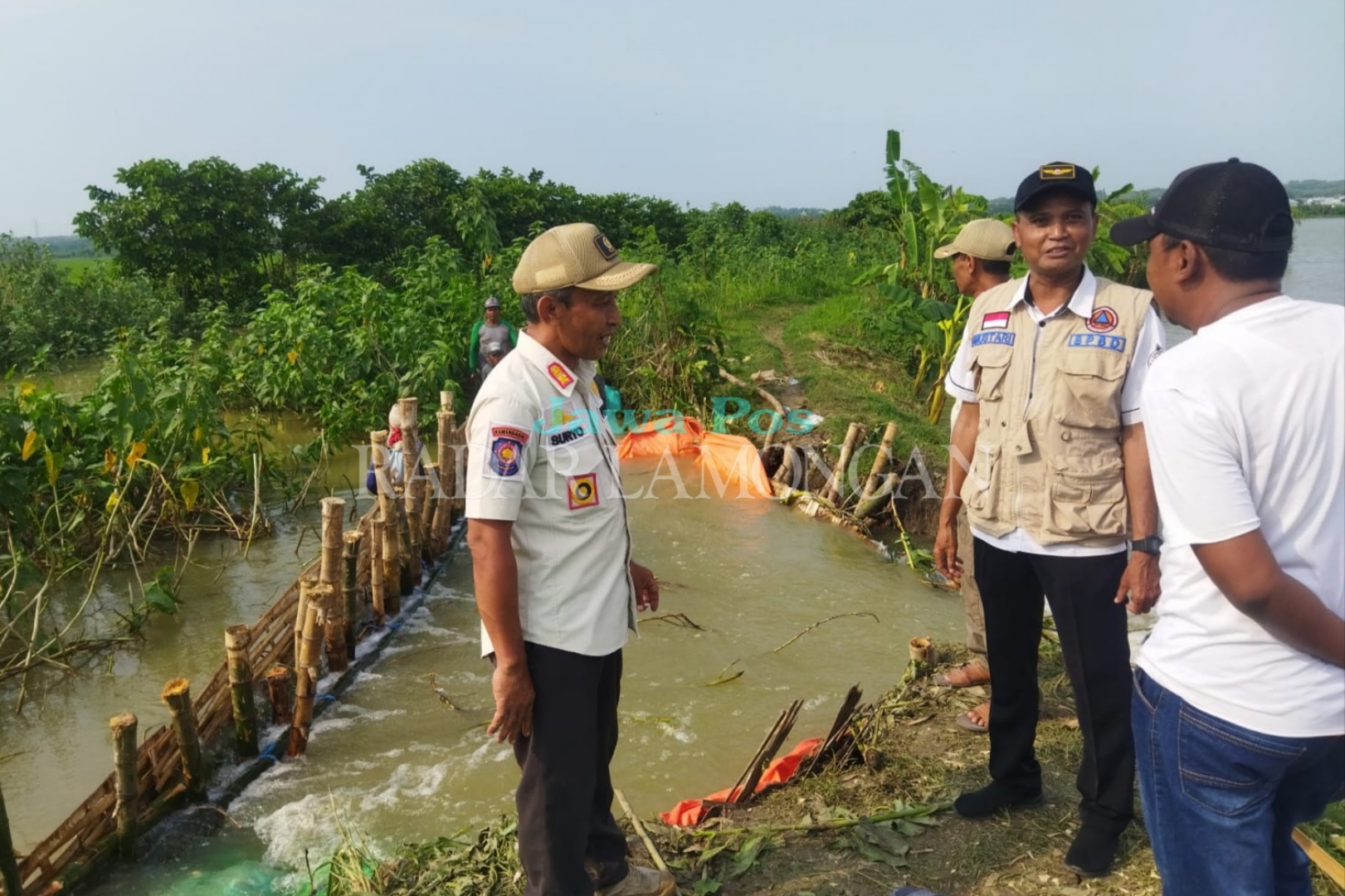TERDAMPAK: Warga bahu membahu menutup sementara titik jebol di sungai Desa Kedungejo, Kecamatan Modo. (Ist. / Radar Lamongan)