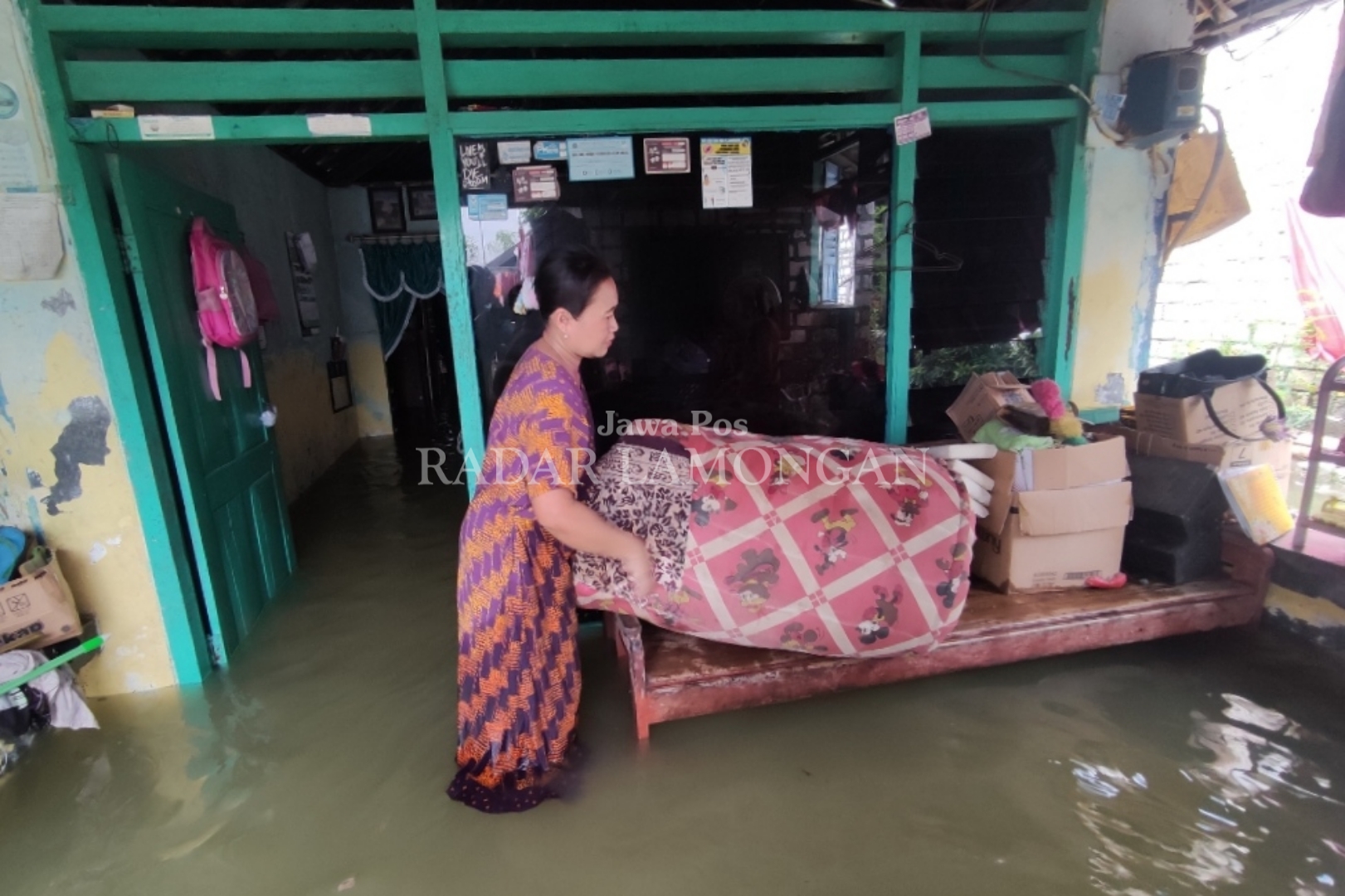 AMANKAN PERABOTAN : Dampak Tanggul Kali Plalangan jebol,Priyatin, warga Dusun Gabus, Desa Tambakploso, Mengamankan perabotan di rumahnya, agar tidak terkena genangan air banjir (Anjar. / rdrlmg)