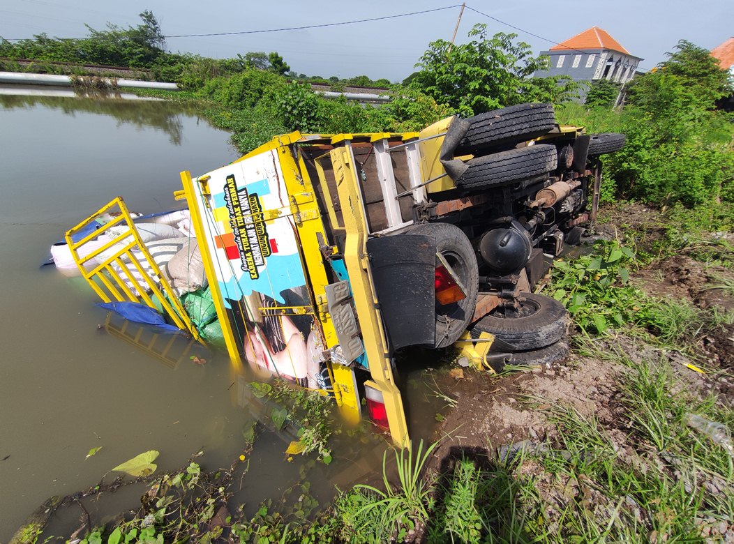 TERGULING KE TAMBAK: Truk AD 9224 EG bermuatan gabah terguling di jalan nasional Lamongan &ndash; Gresik, masuk Desa Pandanpancur, Kecamatan Deket Kamis. (ANJAR DWI PRADIPTA/RDR.LMG)