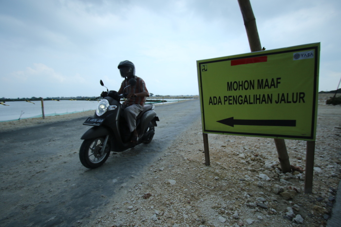 HARAPKAN BAWA MULTIEFEK: Jalan Lingkar Utara Lamongan yang masih pemadatan material dilewati kendaraan roda dua. (ANJAR DWI PRADIPTA/RDR.LMG)