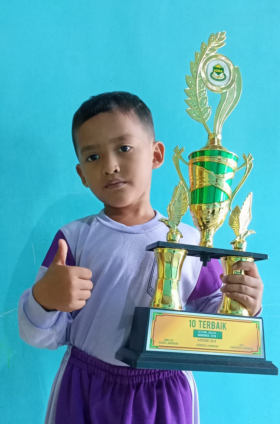 SENANG MANCING: Muhammad Afif Fatihuddin Zain membawa piala sepuluh terbaik Festival Kolase Mamamia 2024. (IST/RDR.LMG)
