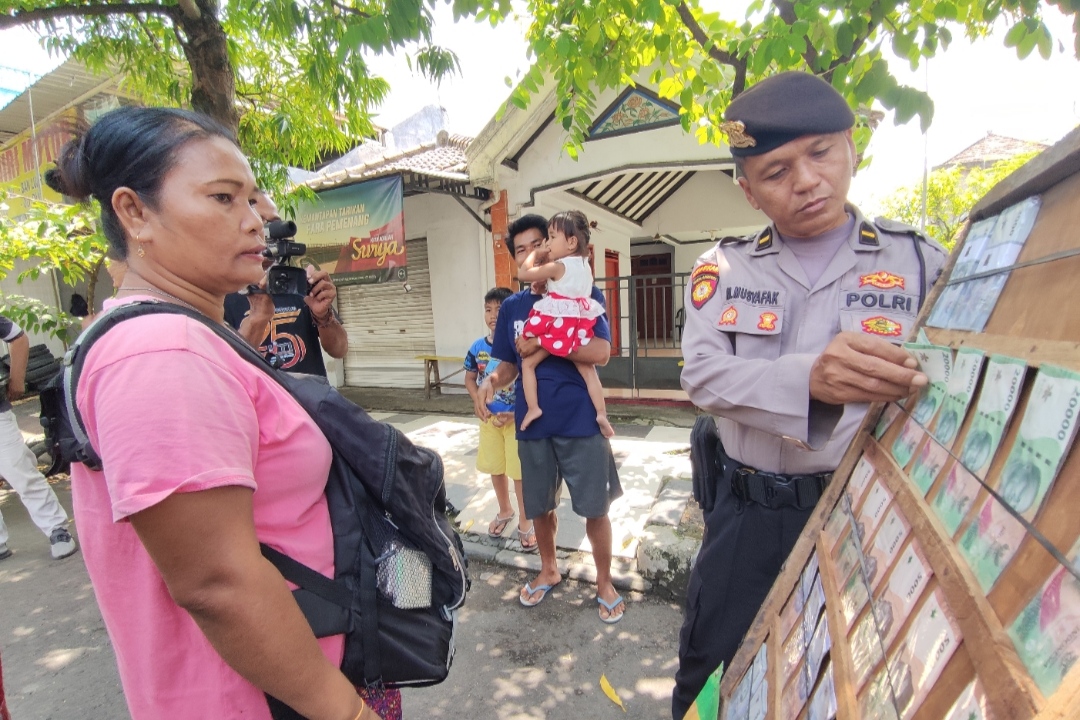 LAKUKAN PENGAWASAN: Petugas Polres Lamongan saat mengecek di salah satu jasa penukaran uang di pinggir Jalan Basuki Rahmad, kemarin (1/4). (Anjar. / Rdrlmg)