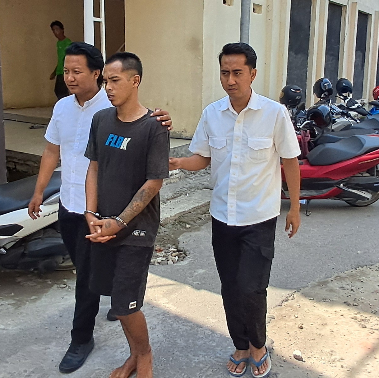 DIBORGOL: Roni Mustofa dikawal dua petugas sebelum menjalani pemeriksaan di Mapolres Lamongan. (GAMAL A/RDR.LMG)