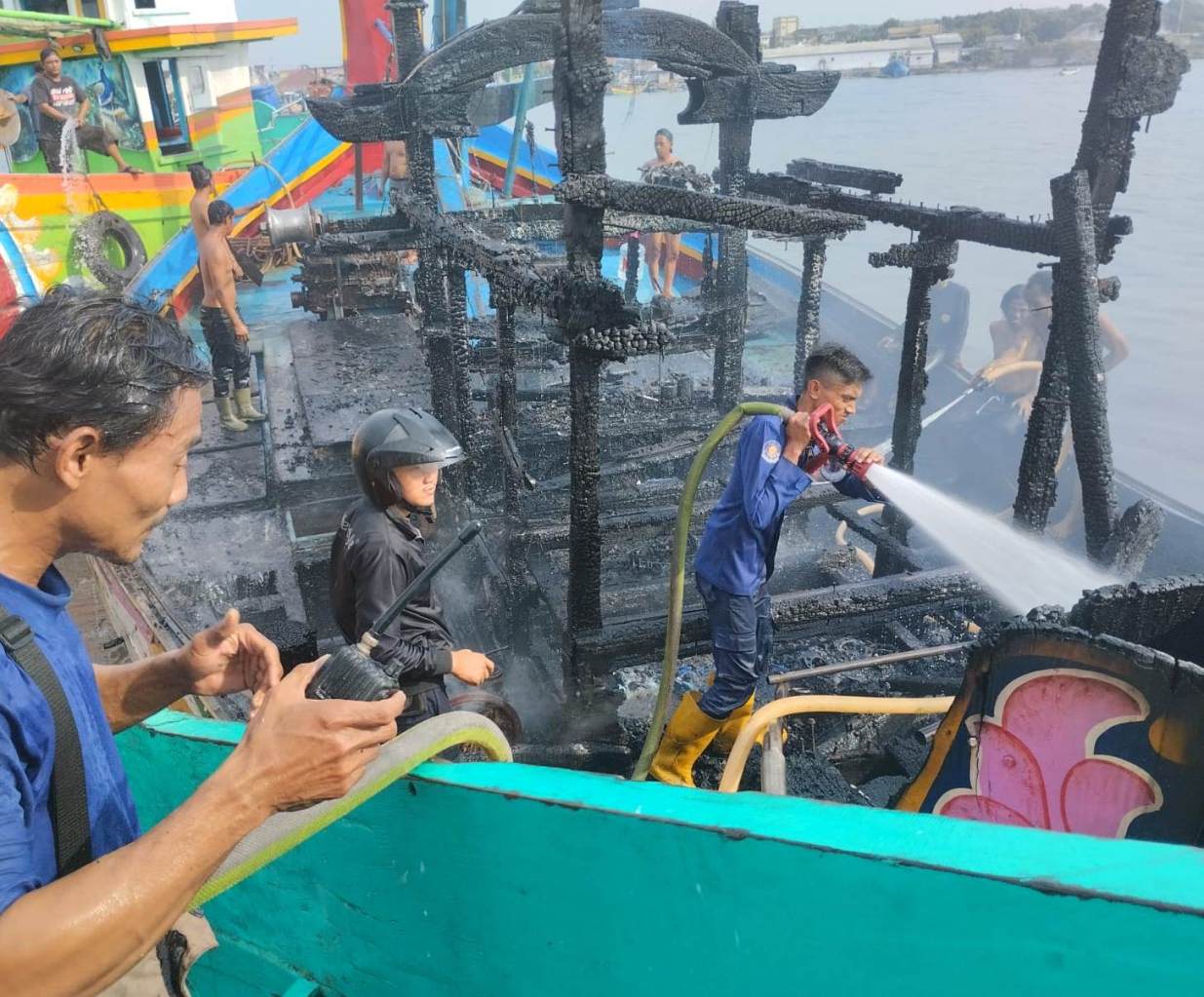 PEMBASAHAN: Petugas menyemprotkan air ke kapal motor nelayan di PPN Brondong. (IST/RDR.LMG)
