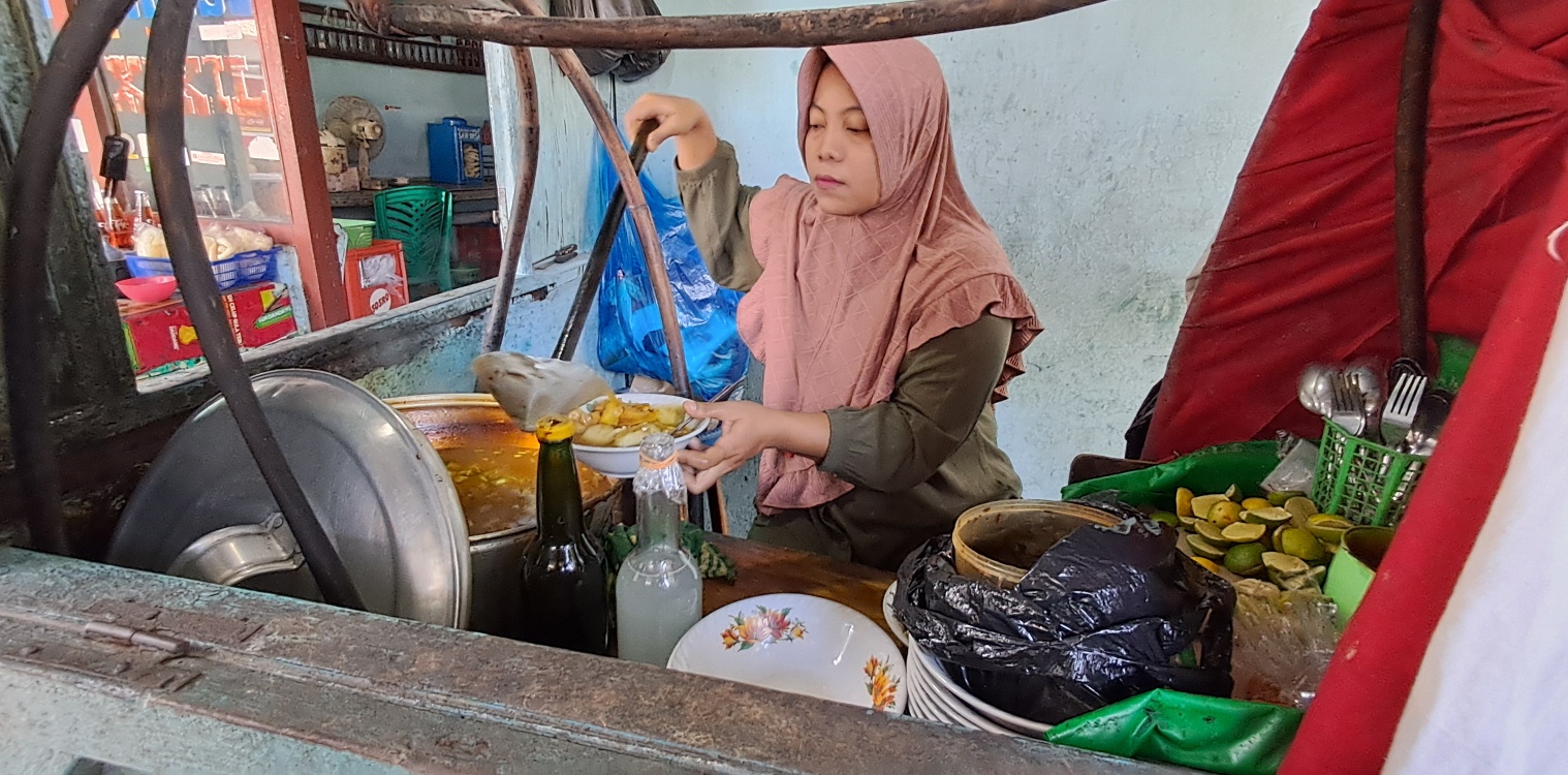 SANG ANAK IKUT MEMBANTU: Ningsih melayani pelanggan lontong kikil di warungnya. (GAMAL A/RDR.LMG)