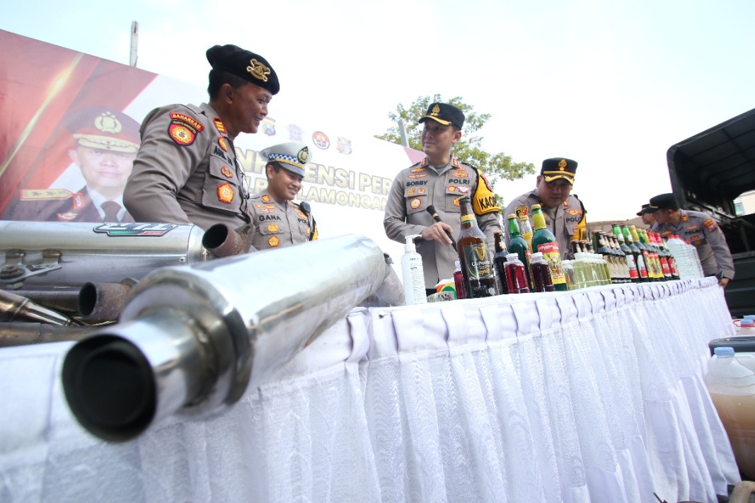 CIPTA KONDISI: Kapolres Lamongan beserta jajaran saat menunjukkan knalpot brong dan ratusan miras beragam jenis.  (Anjar D. Pradipta / Radar Lamongan)