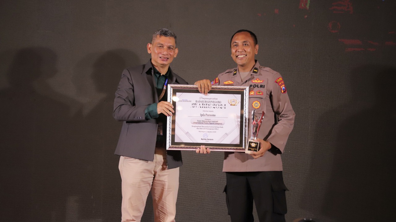 PEGIAT SOSIAL: Ipda Purnomo menerima penghargaan dari Direktur Jawa Pos Radar Bojonegoro Bachtiar Febrianto. (ANJAR DWI PRADIPTA/RDR.LMG)