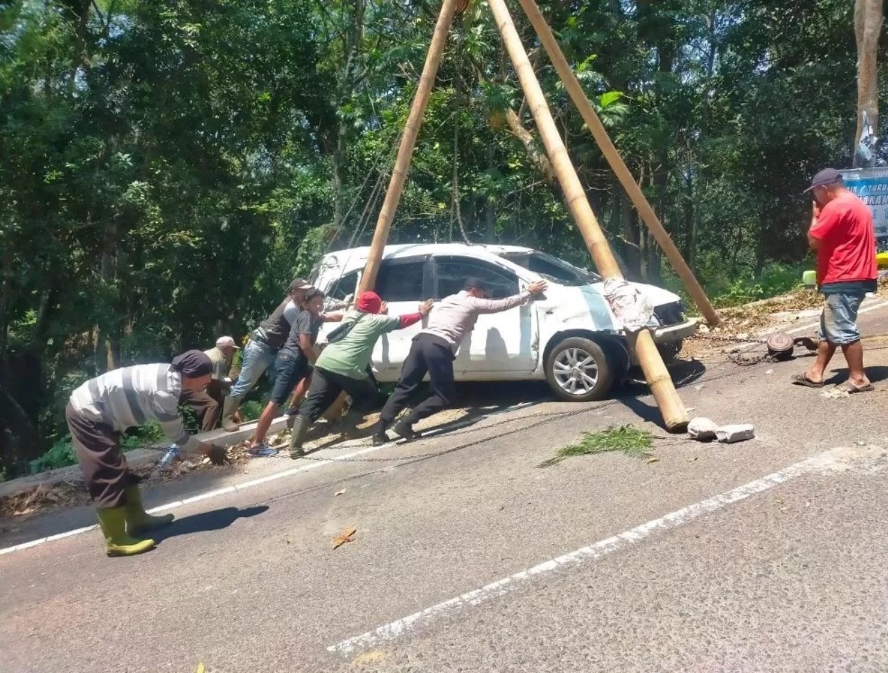 TURUNAN EKSTREM: Petugas Polsek Pacet dan warga mengevakuasi mobil Nissan Grand Livina nopol AD 1761 NH yang masuki jurang jalur Pacet - Cangar. (radar mojokerto/RDR.LMG)