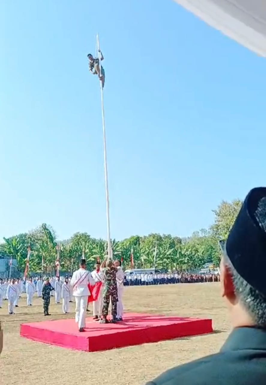 RASA NASIONALISME: Staf Satpol PP Kecamatan Paciran, Abdul Ghofur saat memanjat tiang, akibat tali pengait bendera merah putih putus.