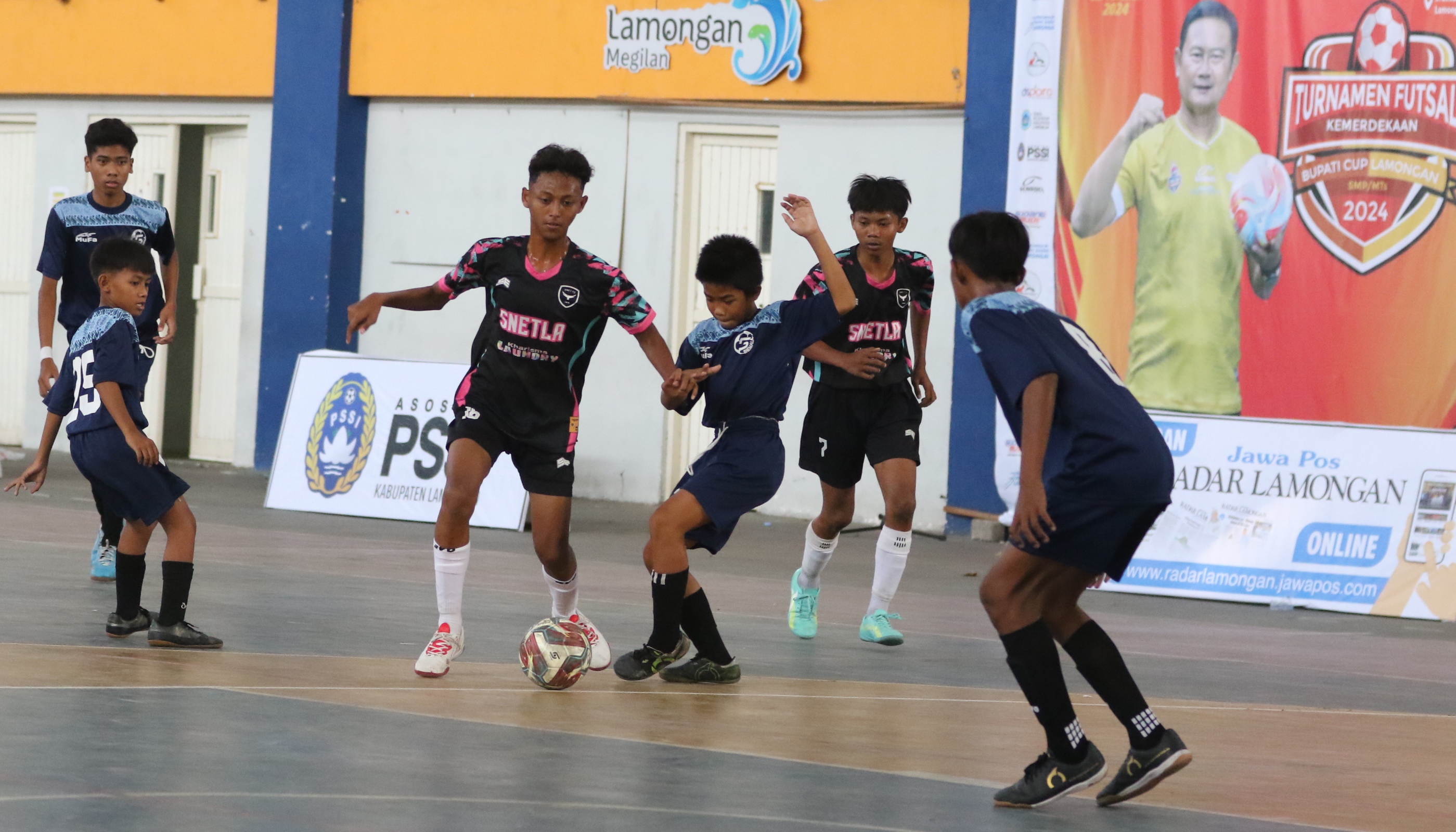 Pemain smpn 1 tikung (tengah) mendribel bola melewati pemain smpn 5 lamongan. (Anjar/Radar Lamongan)