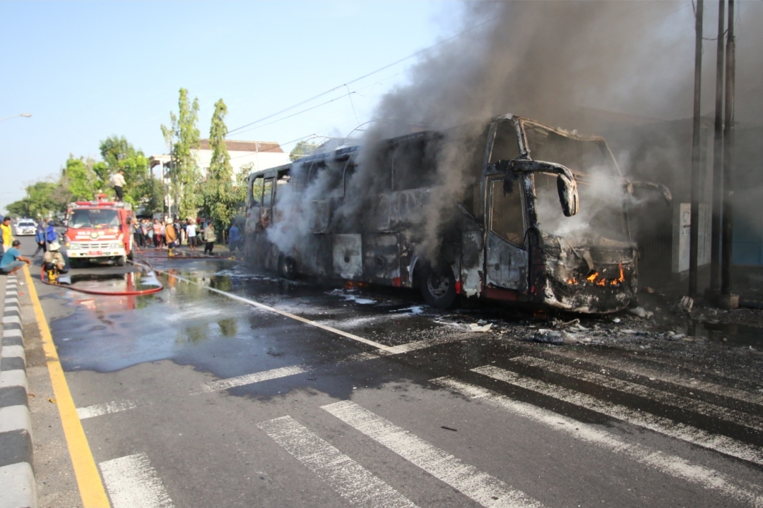 HANGUS: Petugas damkar saat memadamkan bus Medali Mas yang terbakar di jalan nasional Lamongan &ndash; Babat.&nbsp;(Anjar D. Pradipta / Radar Lamongan)