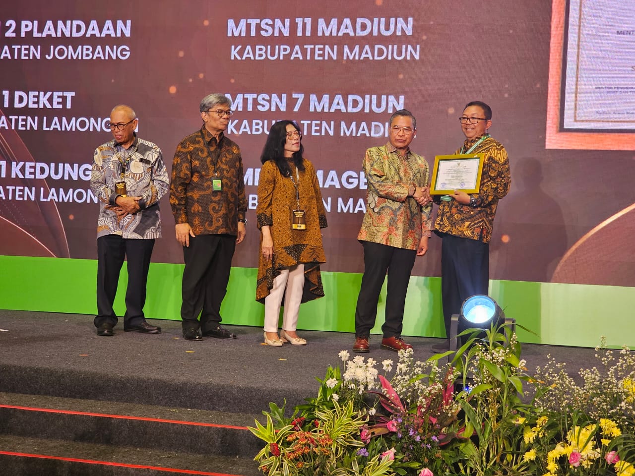 SELAMAT: Kepala SMP Negeri 1 Kedungpring, Tardi menerima penghargaan Adiwiyata Nasional yang diserahkan oleh Wakil Menteri Lingkungan Hidup dan Kehutanan Alue Holong.