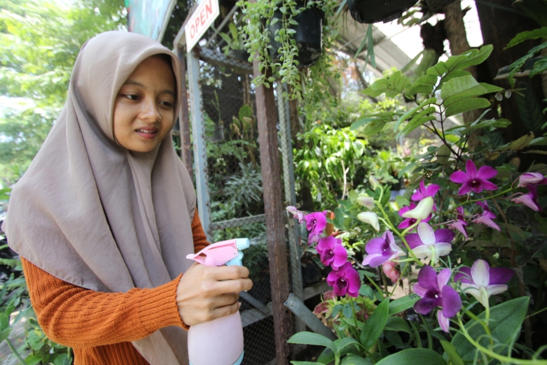 TELATEN: Giska Putri Floraecita saat menyiram salah satu jenis tanaman anggrek.&nbsp;(Anjar D. Pradipta / Radar Lamongan)