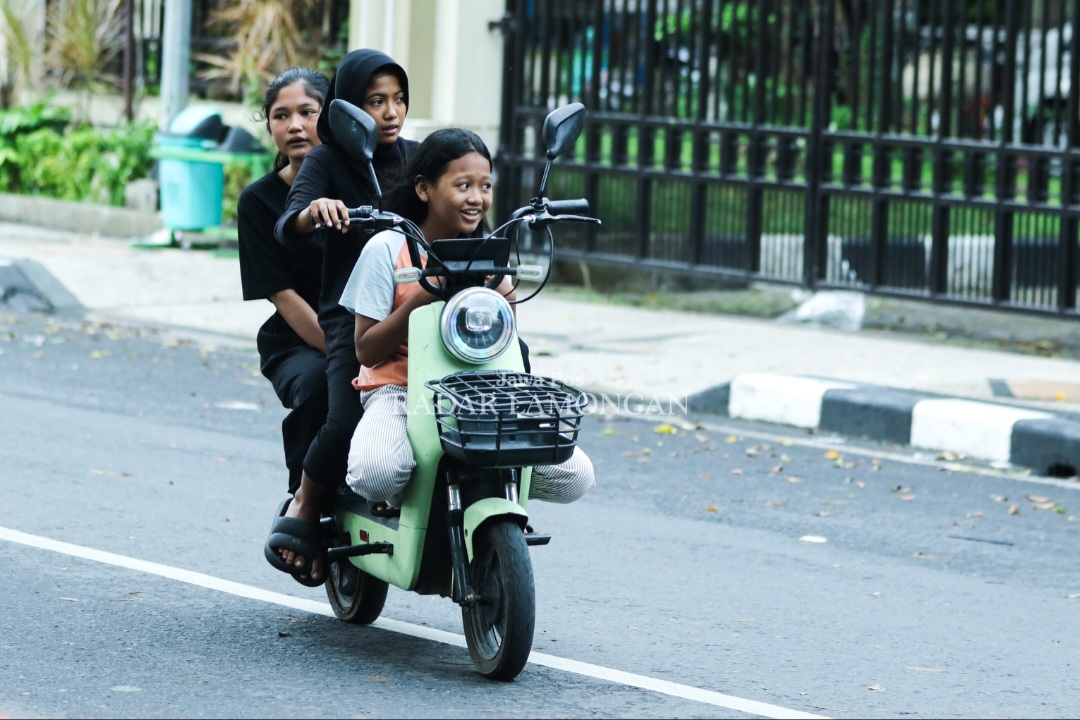MEMBAHAYAKAN: Aksi anak-anak berboncengan tiga mengendarai sepeda listrik di jalan raya. (Anjar D. Pradipta / Radar Lamongan)