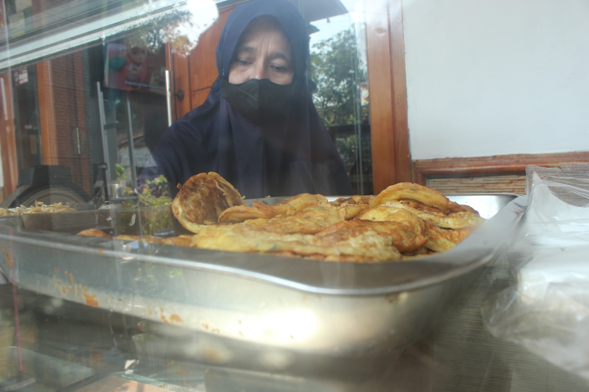 AWALNYA UNTUK ANAK SEKOLAH: Munawaroh melayani pembeli yang datang. Seporsi harga standarnya Rp 6 ribu. (GAMAL A/RDR.LMG)