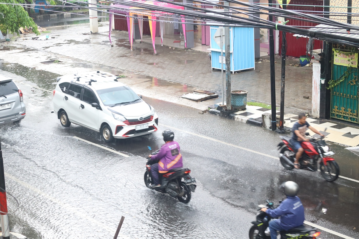 BUTUH PENGECEKAN RUTIN: Air di Jalan Basuki Rahmat Lamongan setelah hujan Rabu. Lubang saluran pembuangan air yang tersumbat sampah dapat mengurangi kecepatan pembuangan air. (ASIP ALAFI A/RDR.LMG)