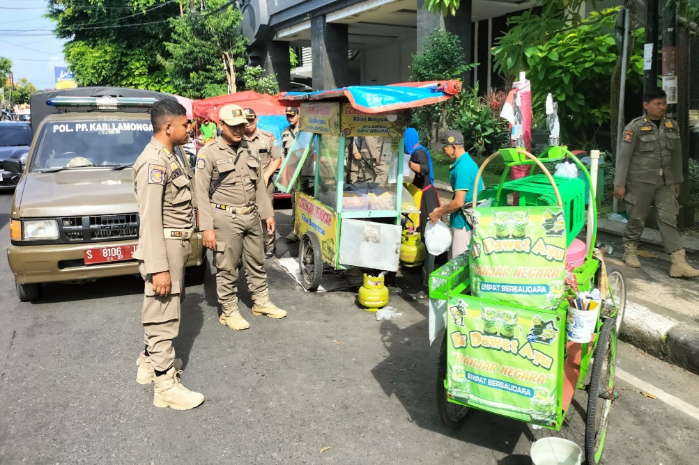 MELANGGAR: Petugas Satpol PP Lamongan saat memberikan teguran kepada PKL yang berjualan di pinggir jalan protokol.