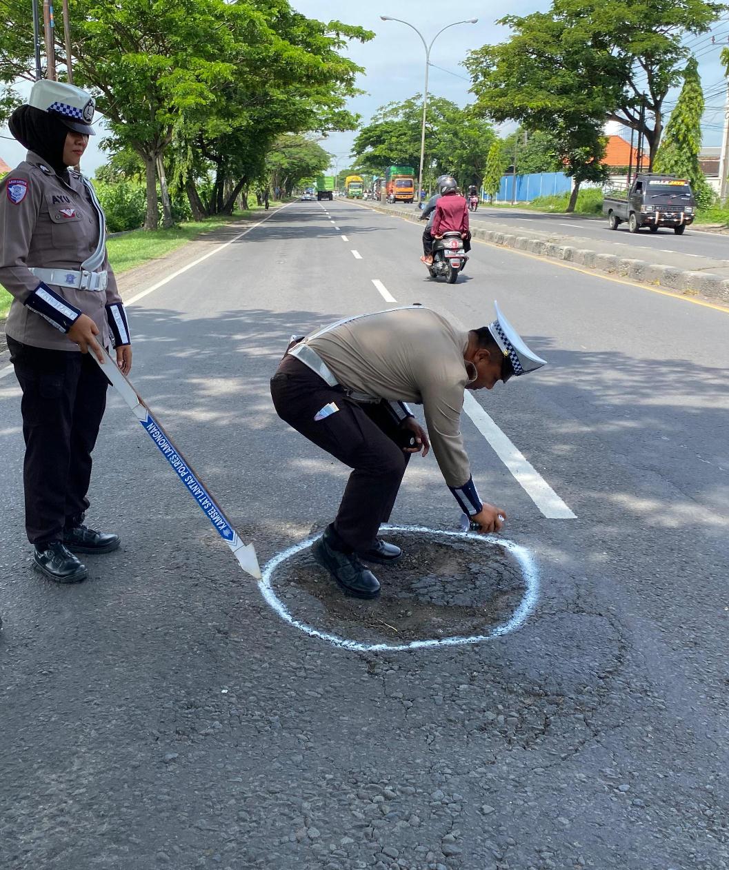 DIBERI TANDA CAT PUTIH: Jalan nasional yang berlubang diberi tanda agar pengguna jalan mengetahuinya. (GAMAL A/RDR.LMG)