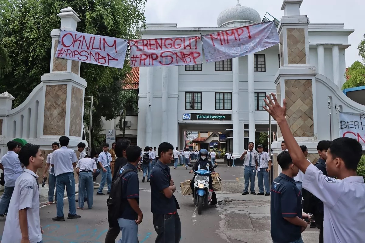 PASANG SPANDUK: Siswa SMKN 2 Solo yang kecewa tak bisa daftar SNBP gelar demonstrasi dan pasang spanduk kritikan di gerbang sekolah, Senin (3/2/2025). (ARIEF BUDIMAN/RADAR SOLO)