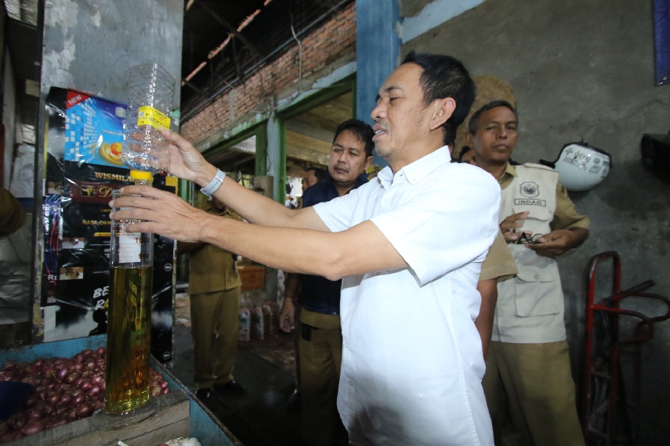 LINDUNGI KONSUMEN: Kepala Disperindag Lamongan, Anang Taufik mengecek langsung takaran MinyaKita di salah satu kios di Pasar Sidoharjo.