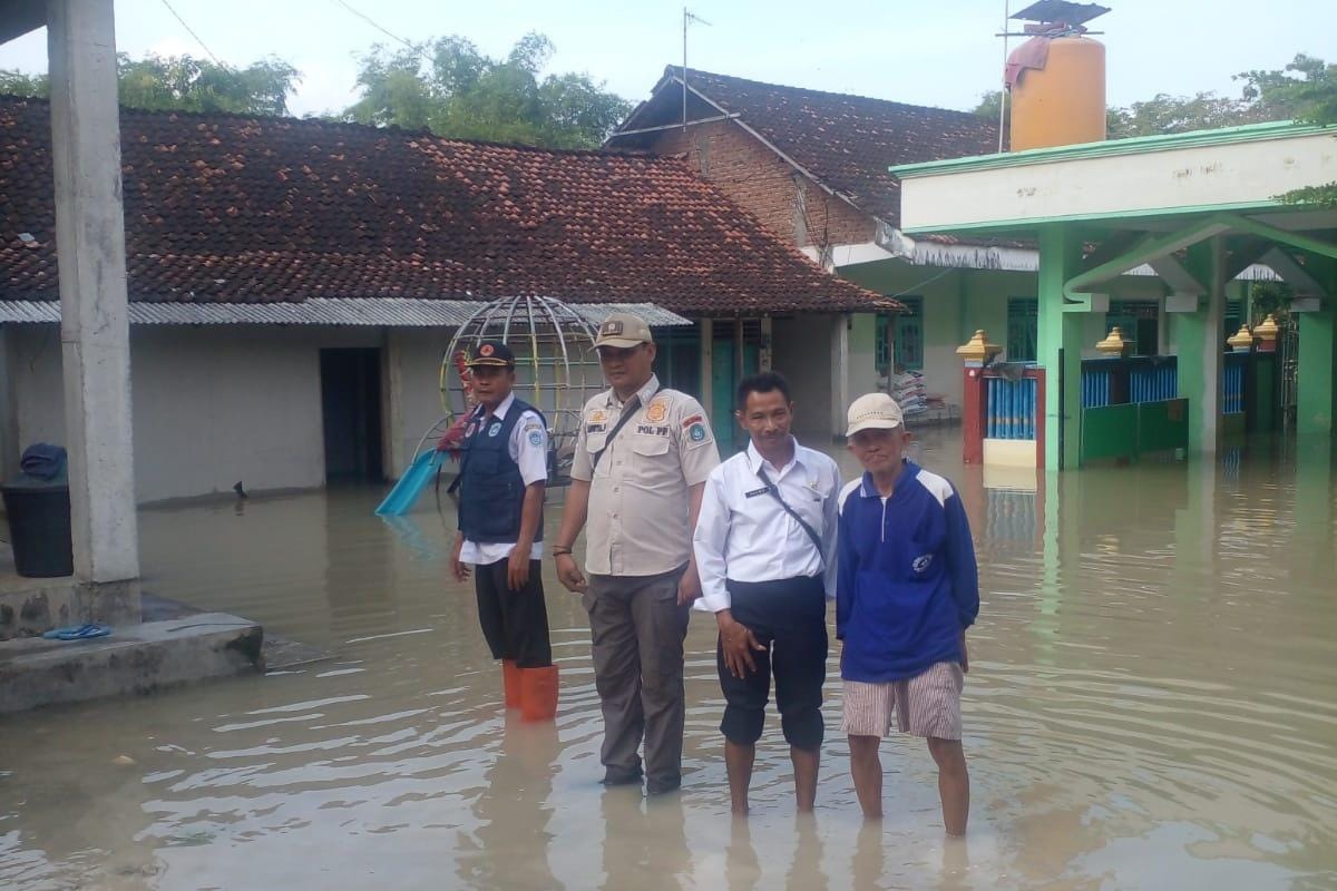 SIAGA: Petugas memantau ketinggian banjir di beberapa titik di Kecamatan Laren, Lamongan.